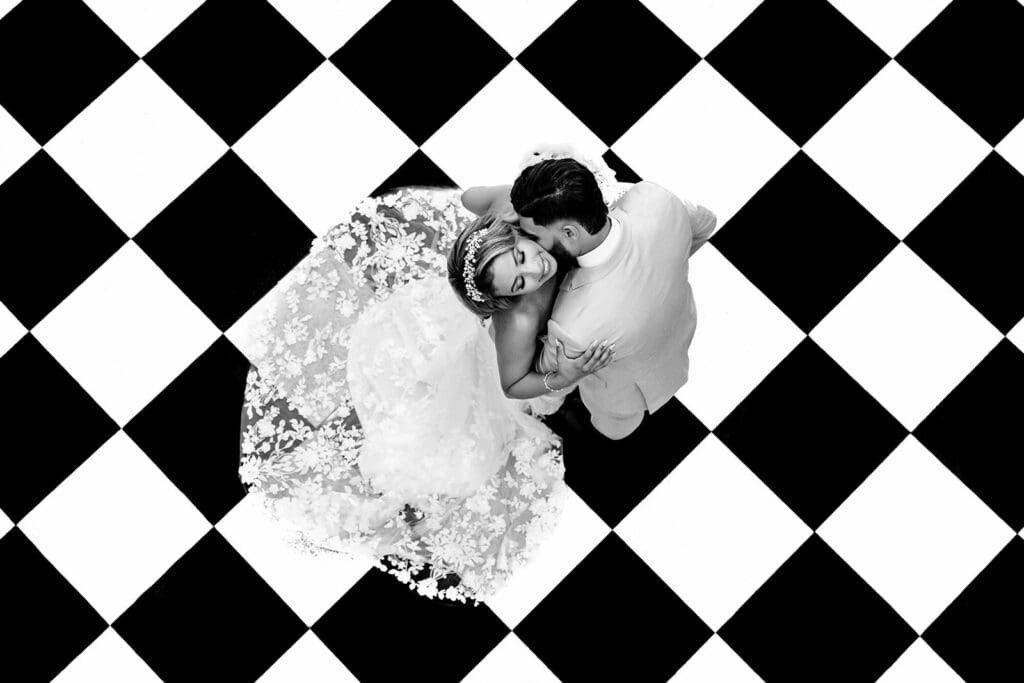 Black and white photo of a bride and groom on a checkered board floor